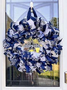 a wreath is hanging on the front door with cowboys letters and stars in blue, white and silver