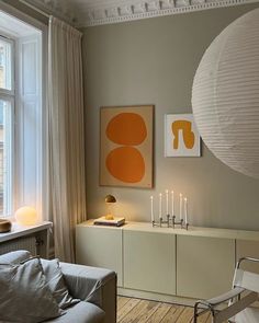 a living room filled with furniture next to a window and a large white paper lantern