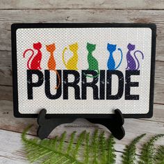 a cross stitch sign that says purrde with cats and rainbow colors on it