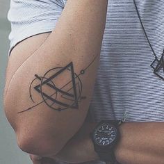 a person with a tattoo on their arm holding a watch and wearing a wrist band