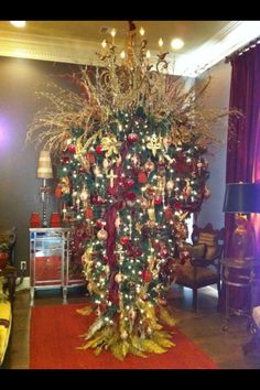 a christmas tree in the middle of a living room decorated with ornaments and lights on it