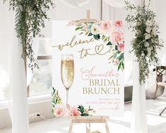 a welcome sign with flowers on it and a glass of champagne in the foreground