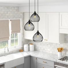 three light fixtures hanging from the ceiling in a kitchen with white cabinets and marble counter tops