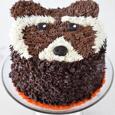 a cake with chocolate icing and white frosting has a raccoon face on it