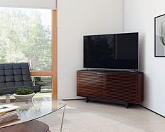 a flat screen tv sitting on top of a wooden entertainment center next to a glass table