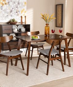 a dining room table and chairs in front of a window with potted plants on it