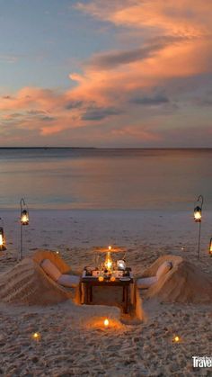 a table set up on the beach with candles