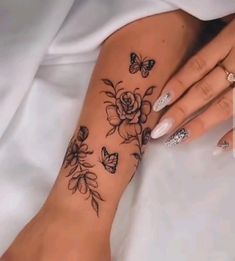 a woman's arm with flowers and butterflies tattooed on her left side, while she is laying down