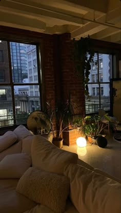 a living room filled with lots of furniture next to a large window covered in plants