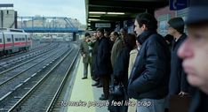 a group of people waiting at a train station for the train to arrive and leave