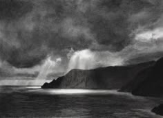 a black and white drawing of storm clouds over the ocean with mountains in the background