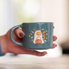 a person holding a coffee mug with a cat on it