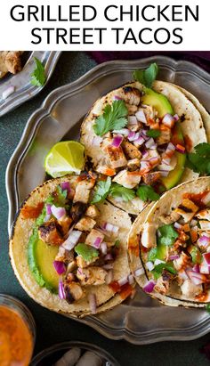 three tacos with chicken, onions and cilantro on a silver platter