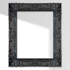 an ornate black framed mirror against a white wall