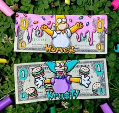 two money bills with cartoon characters painted on them sitting in some green grass and flowers