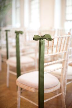 a row of white chairs with green ribbons tied to the back of each chair,