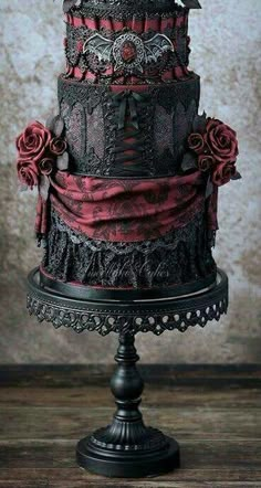 a black and red wedding cake with roses on top