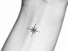 a black and white photo of a small compass tattoo on the left side of the ankle