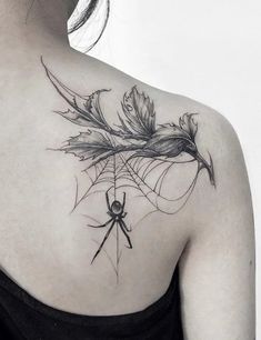 a woman's back with a spider and leaves tattoo on her left shoulder,