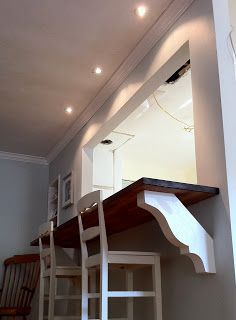 there is a shelf above the kitchen counter with chairs around it and lights hanging from the ceiling