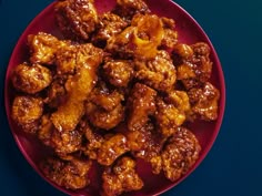 a red plate filled with fried chicken on top of a blue tablecloth next to a knife and fork