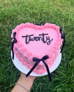 a heart shaped cake with the word twenty written on it in front of someone's hand