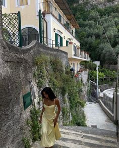 a woman in a yellow dress walking up some steps