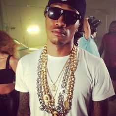 a man wearing sunglasses and a necklace with multiple chains on his neck is standing in front of other people