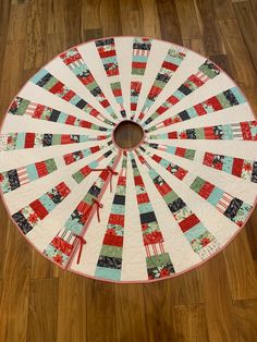 a quilted table topper on the floor with a circular design in red, green and white