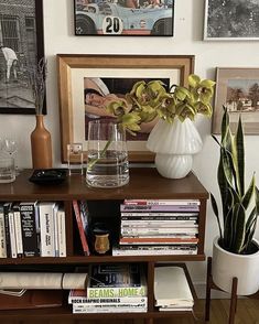 there is a vase with flowers on the shelf next to some books and other items