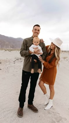 a man and woman holding a baby in the desert