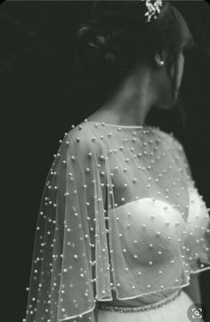 a woman in a wedding dress with pearls on her head and veil over her shoulder