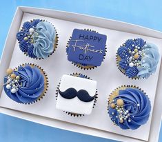 cupcakes decorated with blue frosting in a box