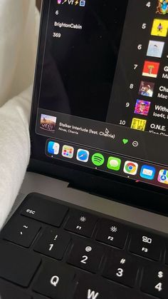 an open laptop computer sitting on top of a white bed next to a pillow and blanket