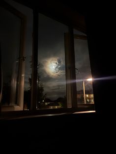 the moon is shining brightly in the dark night sky through an open window with no curtains