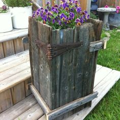 an old wooden bucket with purple flowers in it