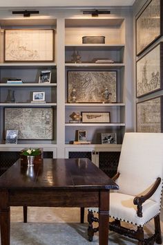 a desk with chairs and bookshelves in a room that has many pictures on the wall