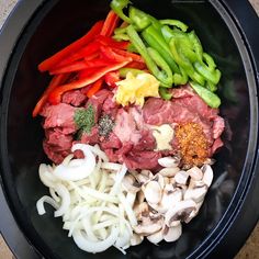 an assortment of vegetables and meat in a black bowl on a counter top, including peppers, onions, mushrooms, and seasonings