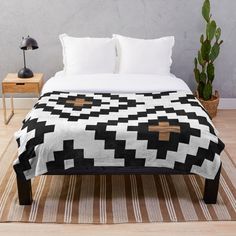 a black and white checkered blanket on a bed with a cactus in the corner