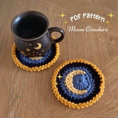 two crocheted coasters sitting on top of a wooden table next to a coffee cup