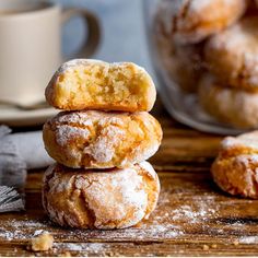 a stack of doughnuts sitting on top of a wooden table next to a cup of coffee