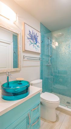 a bathroom with a blue sink, toilet and glass shower stall in the middle of it