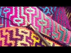 a crochet hook is laying on top of a colorful knitted blanket with an intricate design