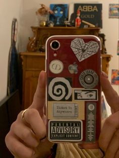 a person holding up a cell phone with many stickers on the back of it