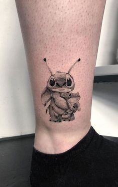 a black and white photo of a small insect tattoo on the right leg, with two smaller bugs in it's legs