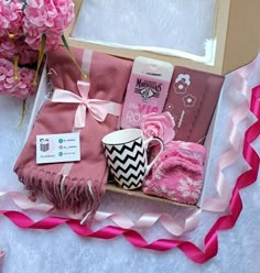 a pink gift box with towels, mitts and other items in it on a table