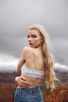 a woman with long blonde hair standing on top of a hill