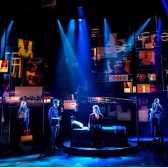 the actors are performing on stage in front of bright blue lights and pictures behind them