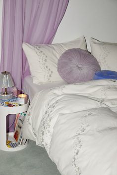 a bed with white sheets and purple drapes