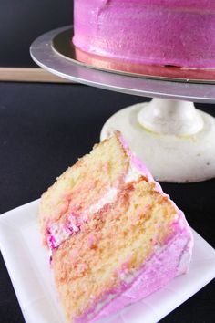 a slice of pink cake on a plate next to the rest of the cake that has been cut